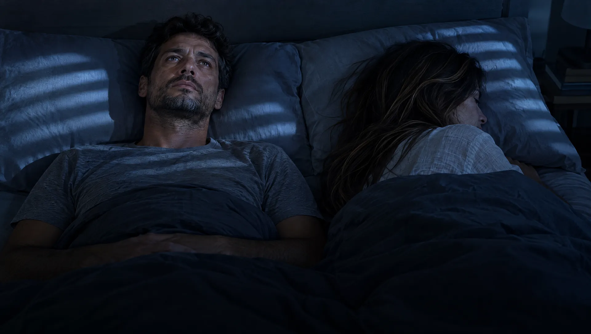 Di notte, lei girata dall'altra parte e lui che fissa il soffitto
