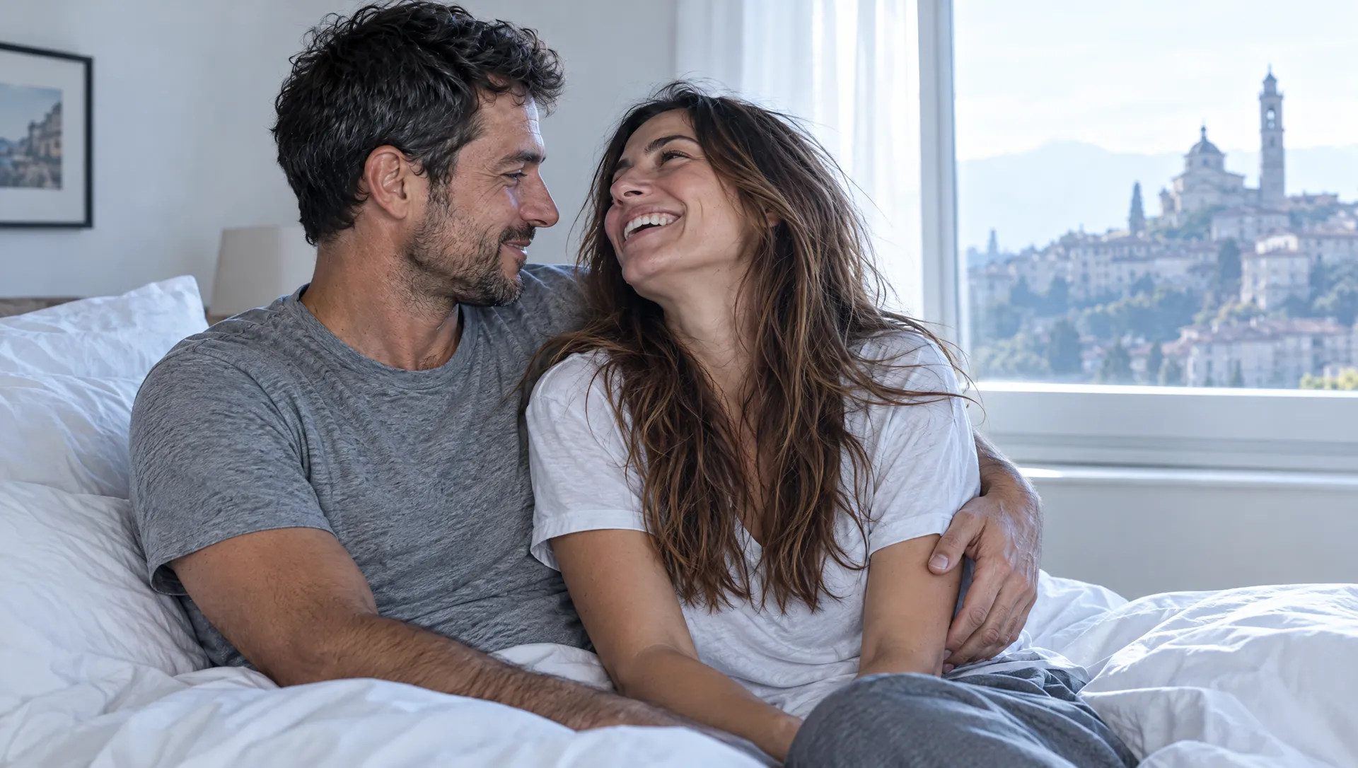 Mattino, lei ride abbracciata a lui nel letto